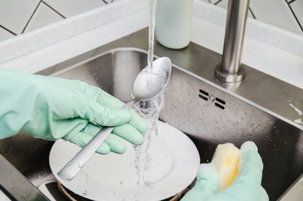 Hand Washing Utensils spoon in a Stainless Steel kitchen Sink